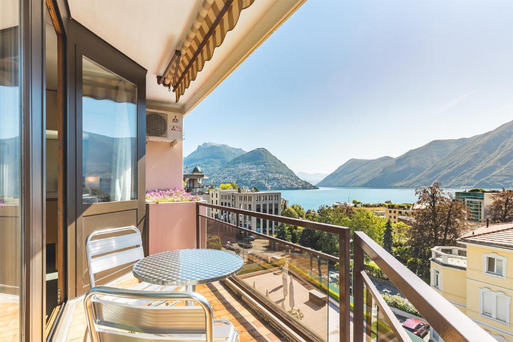 einen Balkon mit einem Tisch und Stühlen sowie Blick auf das Wasser in der Unterkunft Hotel Delfino Lugano in Lugano