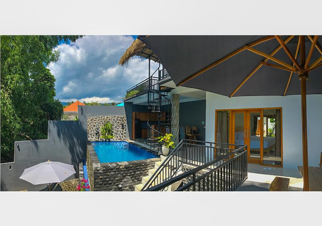 a house with a swimming pool and an umbrella at Villa Manayasa in Lovina
