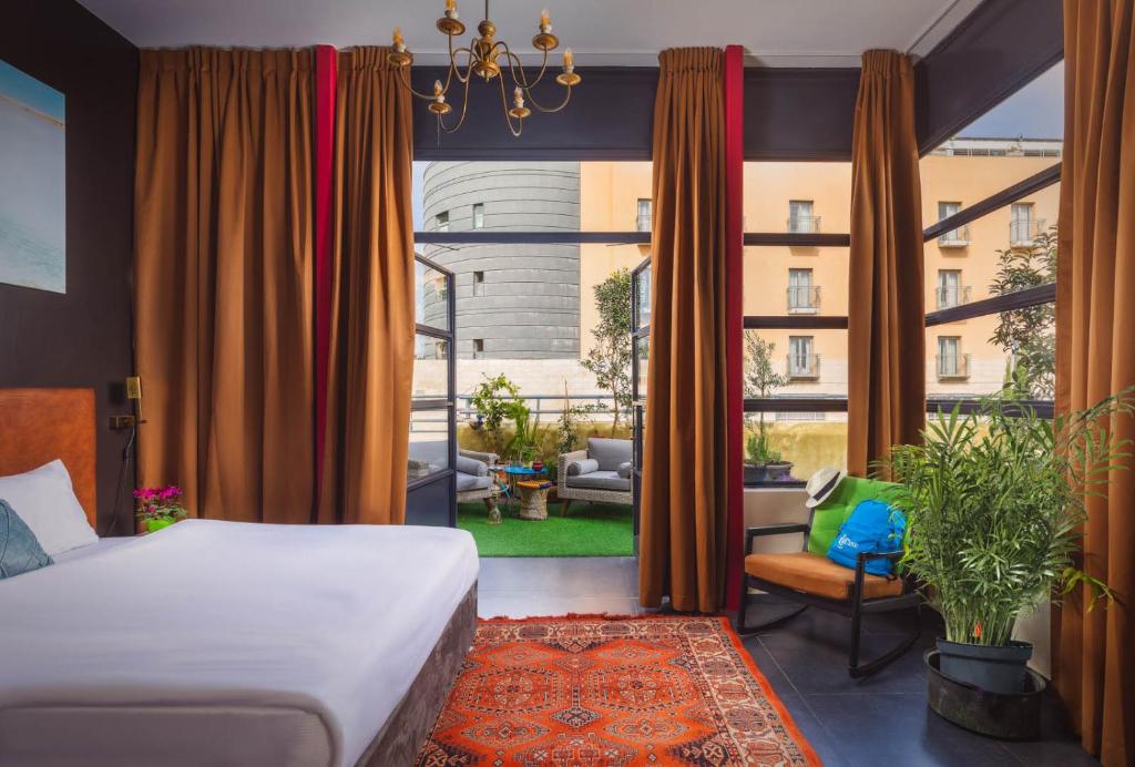 a bedroom with a bed and a large window at INTA Hotel in Tel Aviv
