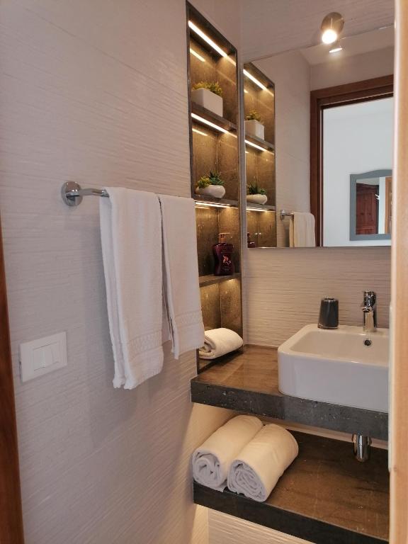 a bathroom with a sink and a mirror and towels at Hotel Antica Cascina Del Golfo in Scopello