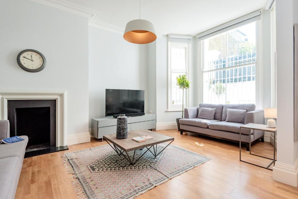 uma sala de estar com um sofá e uma televisão em Stunning Home near Earl's Court by UndertheDoormat em Londres