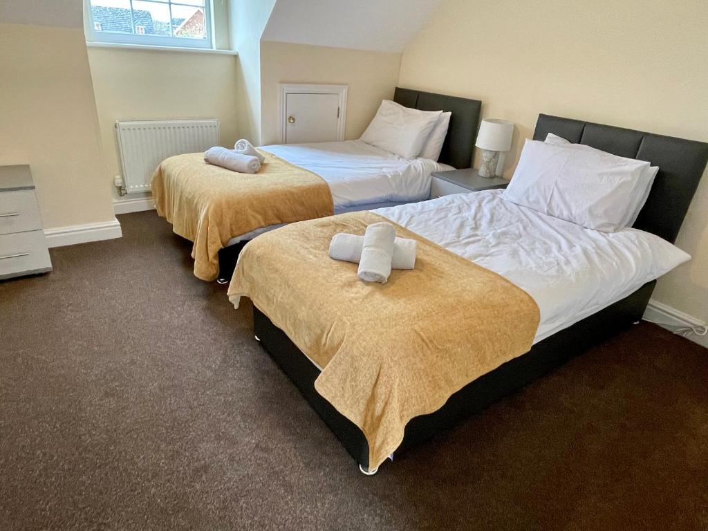 two beds in a hotel room with towels on them at St Margarets House - Modern - 3 Bed Townhouse - Parking - Marvello Properties in Norwich