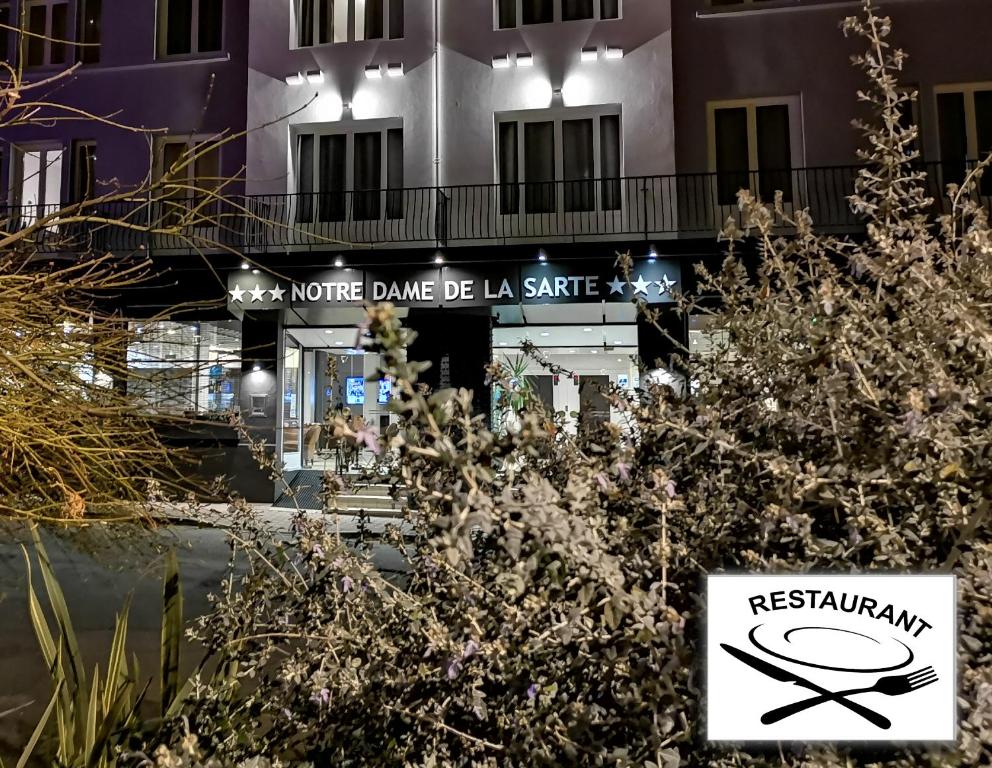 un cartel frente a un edificio con restaurante en Hôtel Notre Dame de la Sarte, en Lourdes