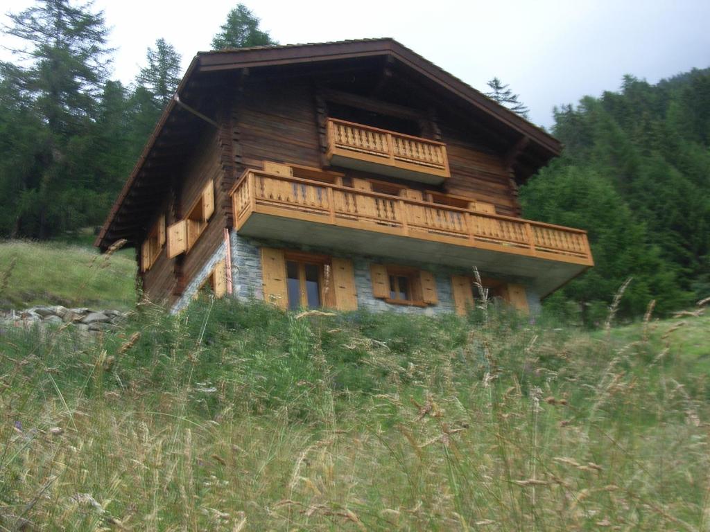 a log cabin with a balcony on top of a hill at Chalet Grouse in Ayer