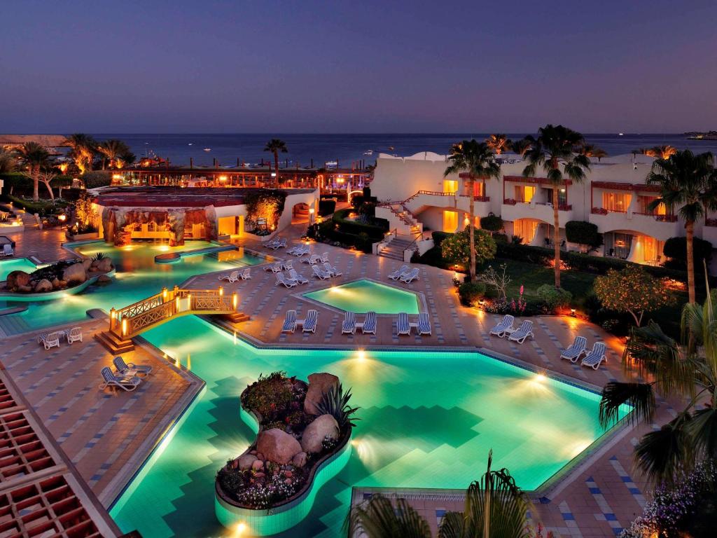 an aerial view of a resort pool at night at Naama Bay Promenade Beach Resort Managed By Accor in Sharm El Sheikh