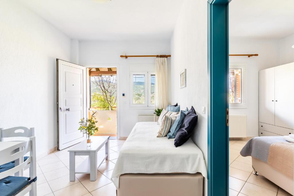 a white bedroom with a bed and a table at Lithos Apartments in Skopelos Town