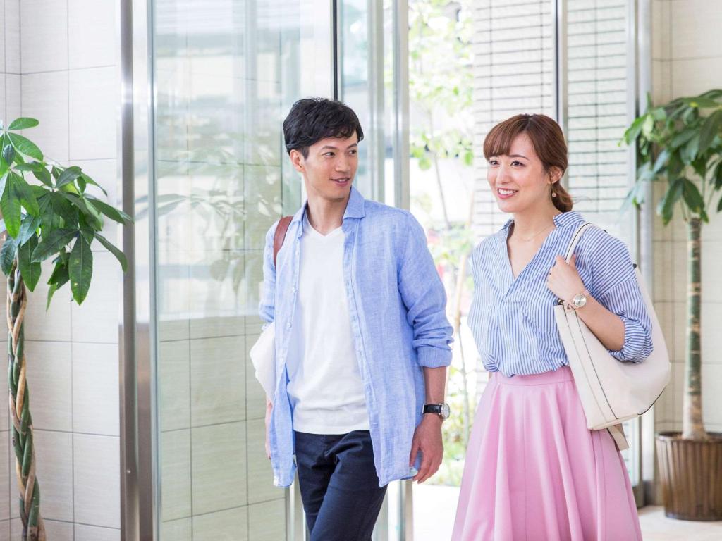 un hombre y una mujer de pie en un edificio en Comfort Inn Fukuoka Tenjin, en Fukuoka