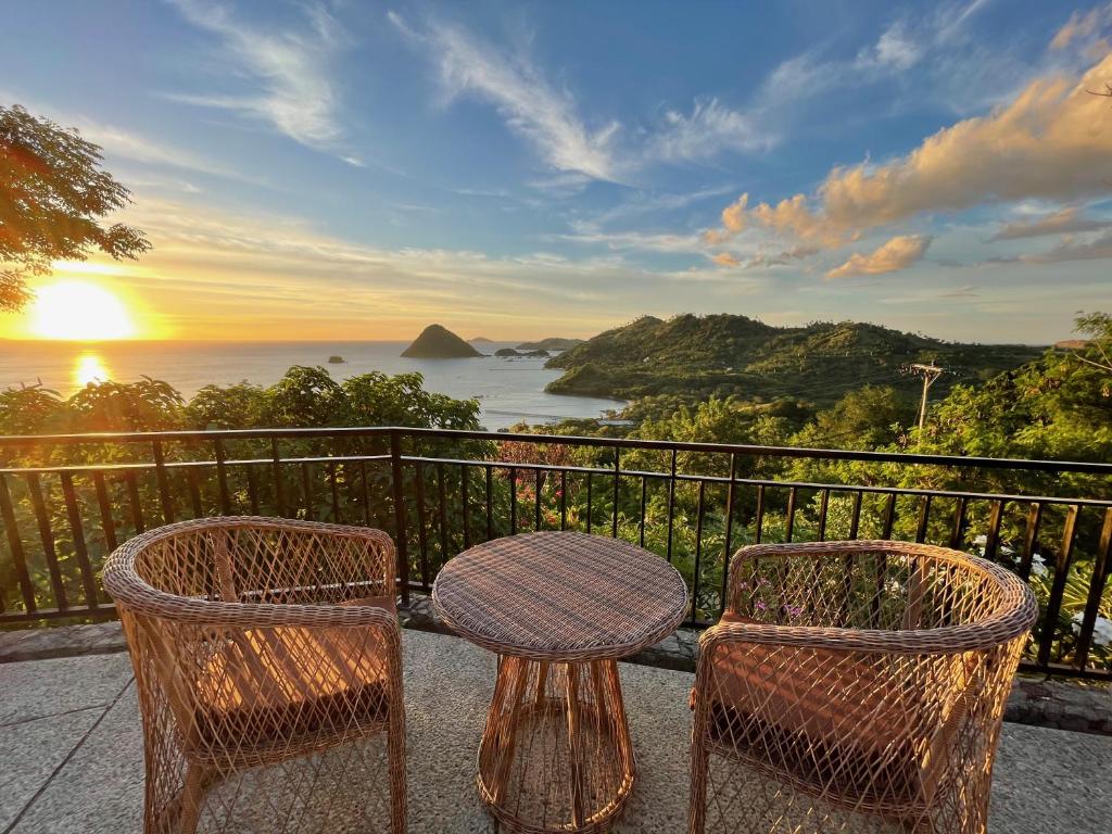 einen Tisch und Stühle auf einem Balkon mit Meerblick in der Unterkunft Elang Hillside Bamboo Villas in Labuan Bajo