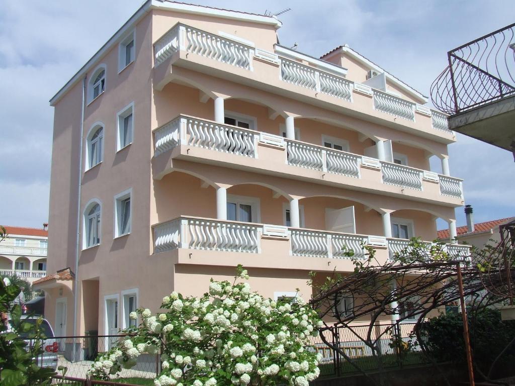 a building with balconies and a tree in front of it at Rooms and Apartments Ana in Zadar