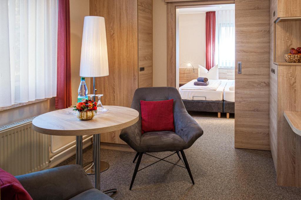 クロルト・アルテンベルクにあるPension Hotel Sartorのテーブル、椅子、ベッドが備わる客室です。