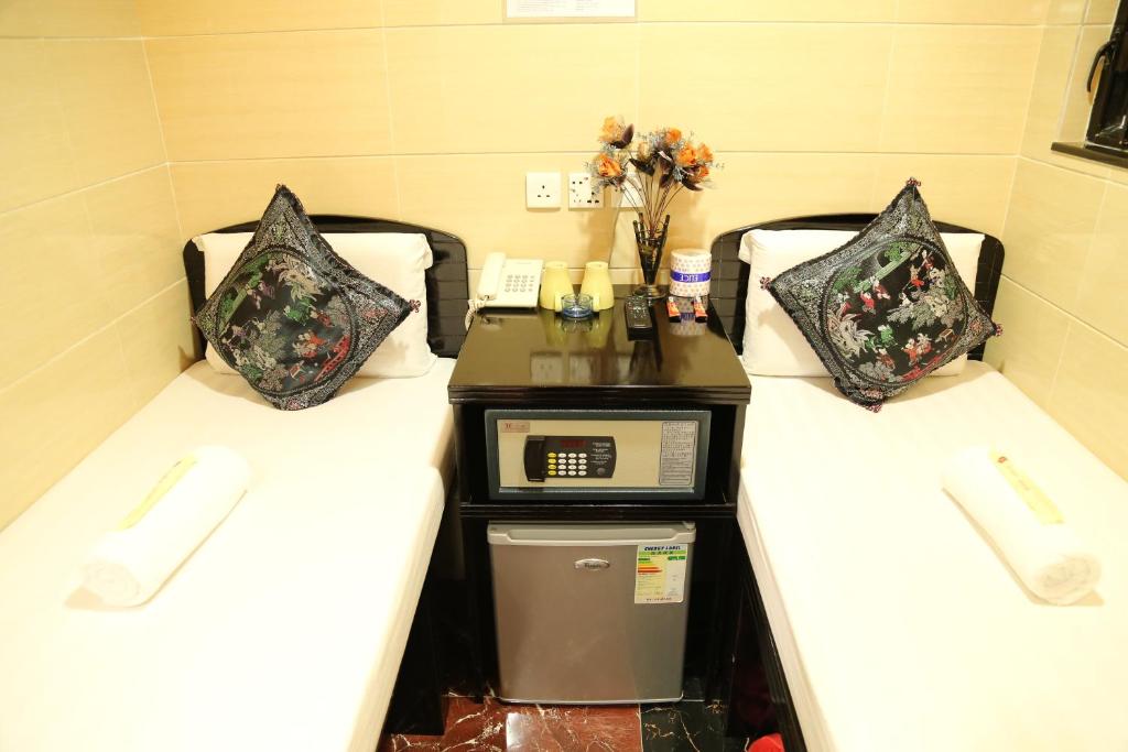 two beds in a hotel room with a desk on the middle at Narli Guest House in Hong Kong