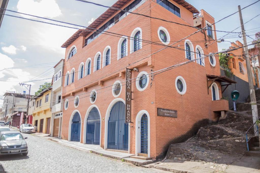 a brick building with round windows on a street at Pousada Rio Branco Nova Lima - By UP Hotel in Nova Lima