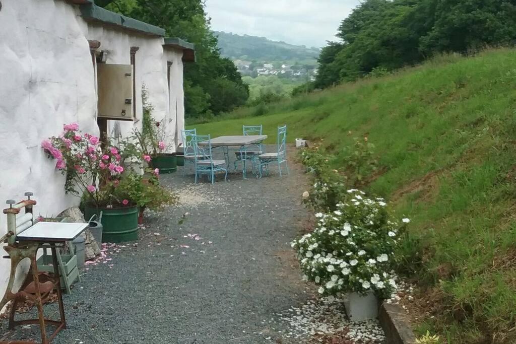 a house with a table and chairs and flowers at Stables,1 or 2 bedroom Eco earth house, edge of Dartmoor in South Brent