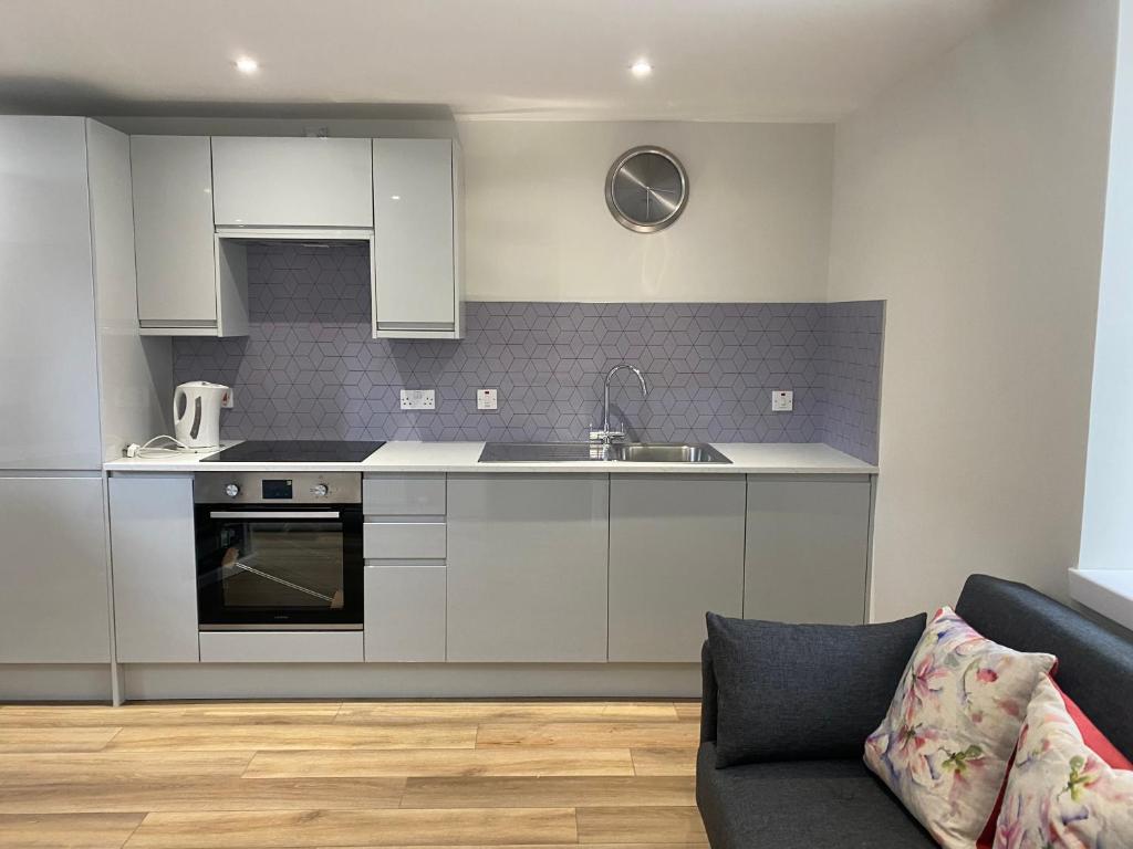 a kitchen with white cabinets and a sink and a couch at Holborn Apartment in Thurso