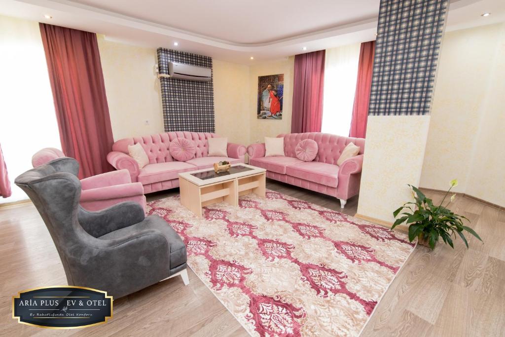 a living room with pink couches and a rug at aria plus ev-otel in Çiftlikköy