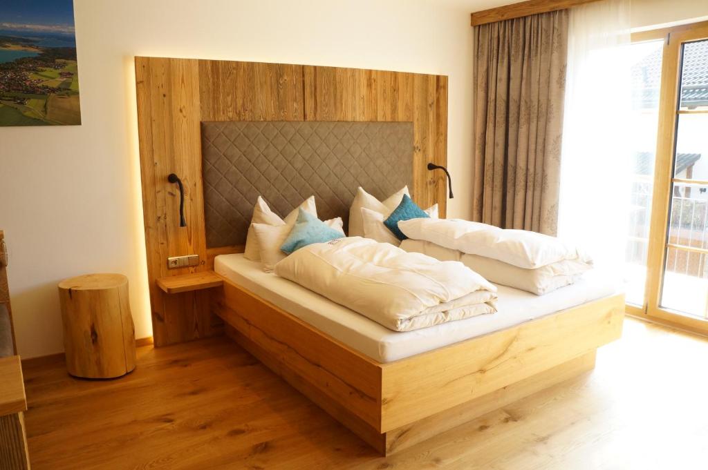 Schlafzimmer mit einem Bett mit weißer Bettwäsche und blauen Kissen in der Unterkunft Der Obere Wirt zum Queri in Andechs