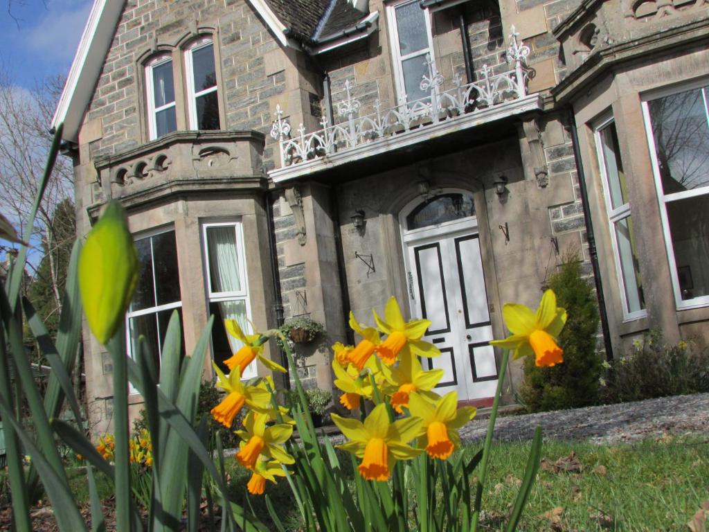 an old house with flowers in front of it at Arden House in Kingussie