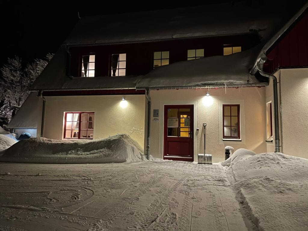 ein Haus mit Schnee auf dem Boden davor in der Unterkunft Zur Bergwiese 5 Sterne Appartementhaus in Fürstenau