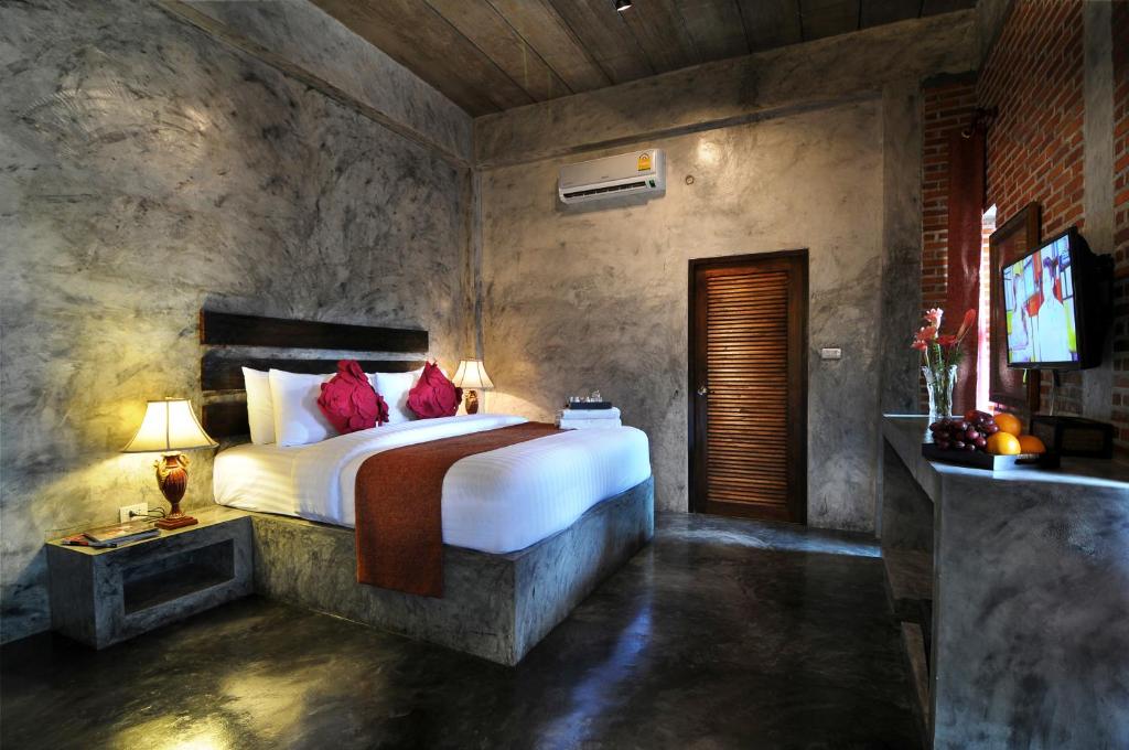 a bedroom with a large bed and a television at Love Bridge House บ้านสะพานรัก in Sangkhla Buri