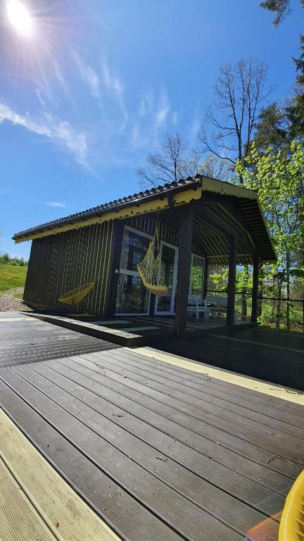 un edificio con un paseo marítimo de madera en un parque en VIP Yellow dream house Sodyba Geras en Anykščiai