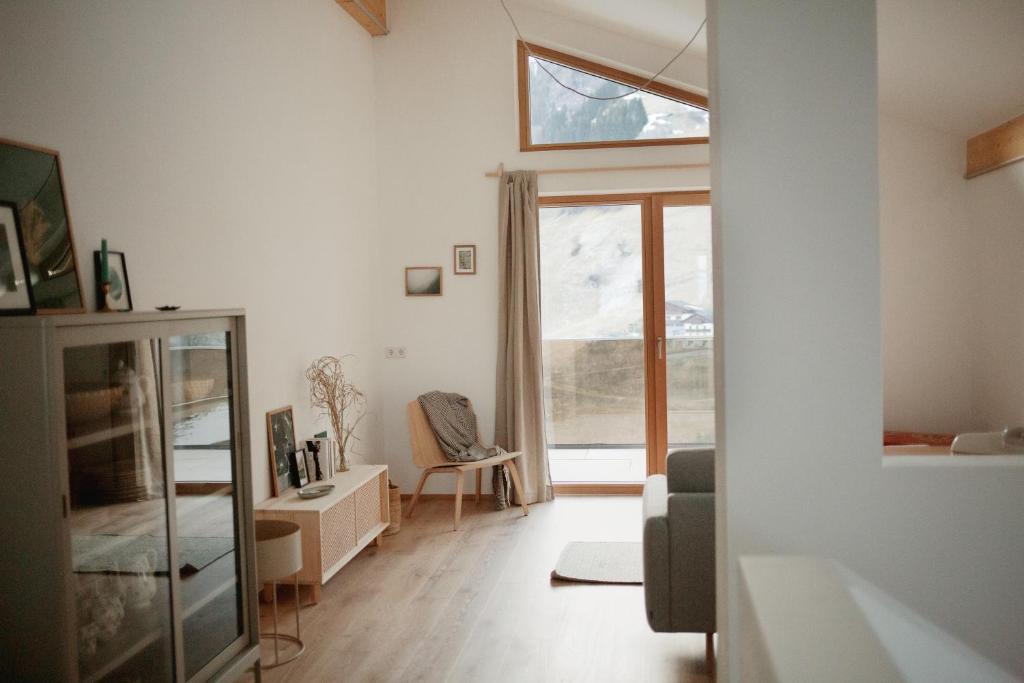 Bergauf Appartement في غروسارل: غرفة معيشة مع نافذة وكرسي