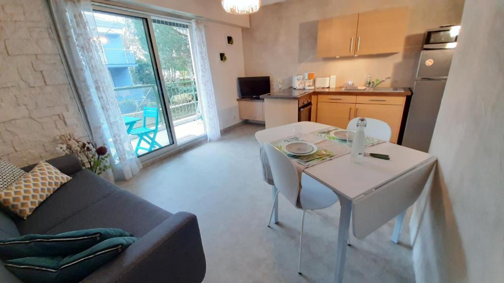sala de estar con mesa blanca y cocina en LA BIGEONNIERE Appartement 1 chambre résidence avec piscine proche centre, en Saint-Jean-de-Monts