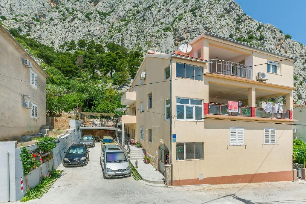 un edificio de apartamentos con coches aparcados frente a una montaña en Apartment Goge, en Omiš