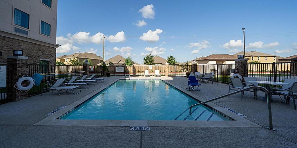 a swimming pool with chairs and a person sitting in a chair at Staybridge Suites - Houston NW Cypress Crossings , an IHG Hotel in Houston
