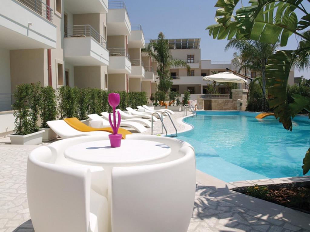 - une piscine avec une table et des chaises à côté d'un bâtiment dans l'établissement Santa Caterina Resort, à Santa Caterina
