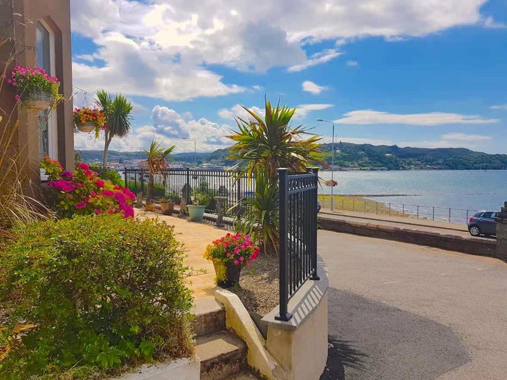 a balcony with plants and flowers and a body of water at Corriemar House in Oban