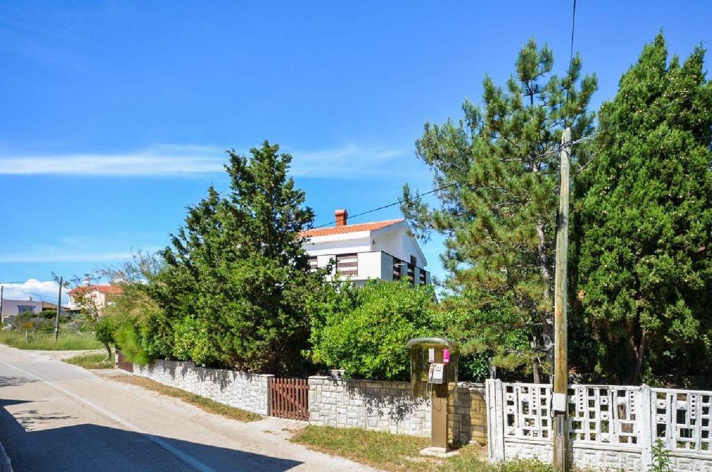 een wit hek voor een huis met bomen bij Apartment Krekovic in Pag