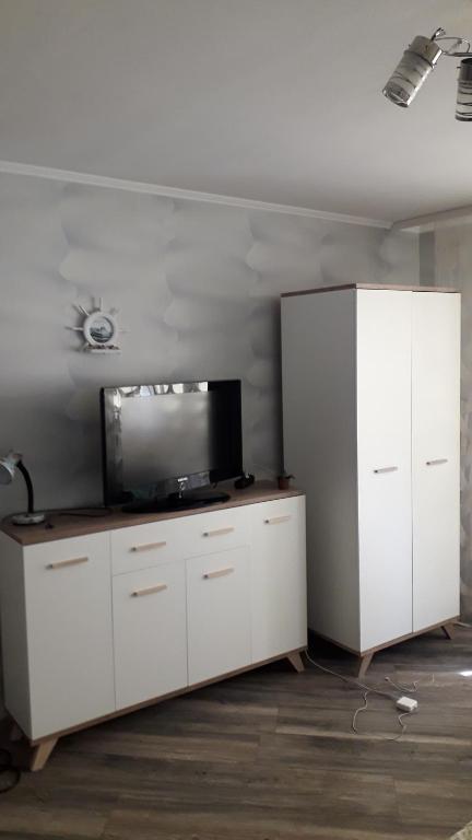a living room with a tv and white cabinets at Siguldas Street Apartment in Ventspils in Ventspils
