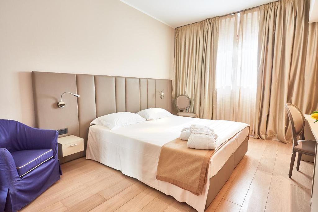 sypialnia z dużym łóżkiem i niebieskim krzesłem w obiekcie Ferretti MajesticHouse w mieście Castenedolo