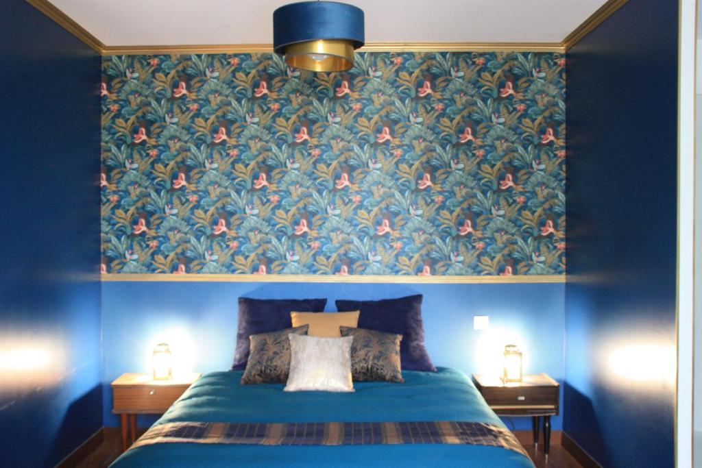 a bedroom with a blue bed with a floral wallpaper at Le Clos de la Canardière in Savigny-sur-Braye
