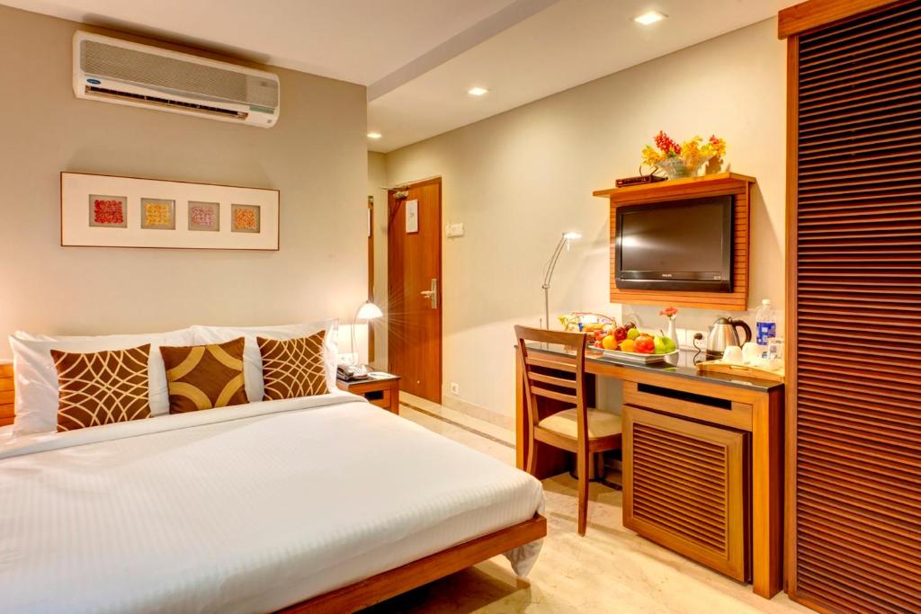 a bedroom with a bed and a desk with a television at Hotel Casa Fortuna in Kolkata