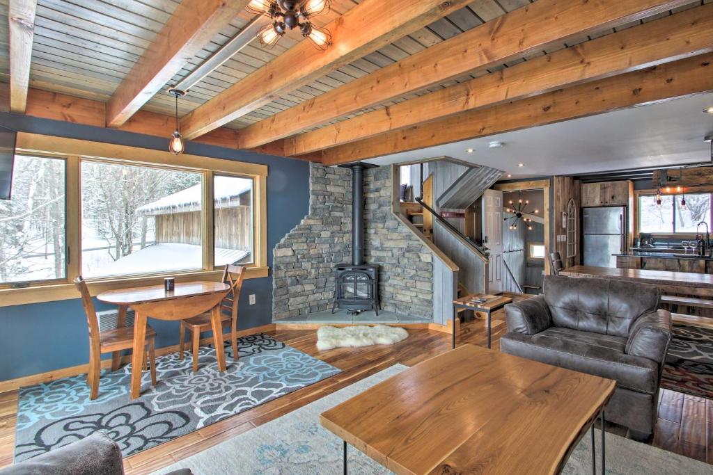 uma sala de estar com uma lareira de pedra e uma mesa em Ski-InandOut Burke Mtn Condo with Amenity Access! em East Burke