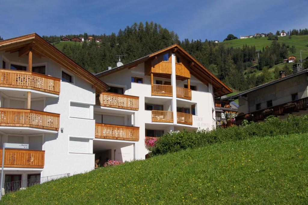 um edifício branco com varandas de madeira numa colina em L'GROF - AL CONTE em San Martino in Badia