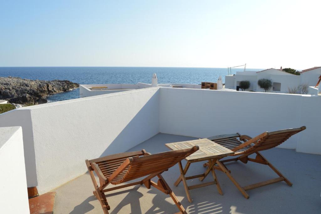 dwa krzesła i stół na balkonie z widokiem na ocean w obiekcie BINIPARADISE - Villa Excellent w mieście Binibeca