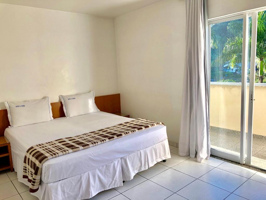 a bedroom with a bed and a large window at Dom Pedro Hotel in Petrópolis