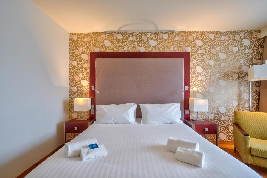 a bedroom with a large bed with two towels on it at Zenitude Relais &amp; Spa - Paris Charles de Gaulle in Roissy-en-France