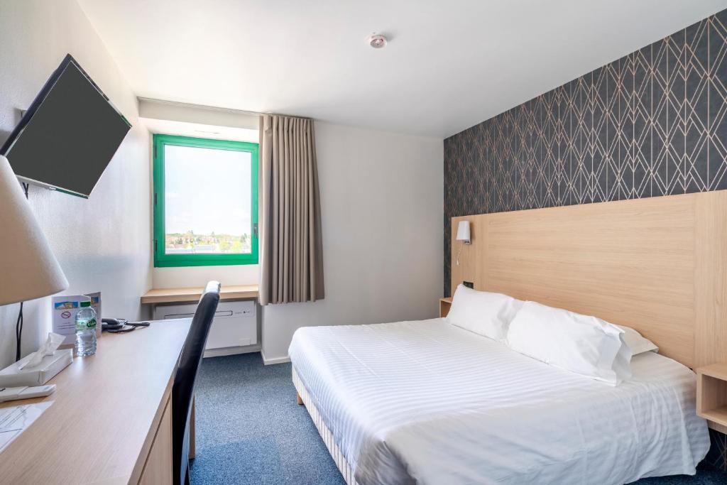 ロモランタンにあるCit Hotel LA PYRAMIDEのベッドとデスクが備わるホテルルームです。