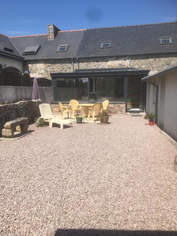 eine Terrasse mit Stühlen und einem Tisch und einem Gebäude in der Unterkunft Le Cottage " Village de La Ruée " Location de vacances in Plurien