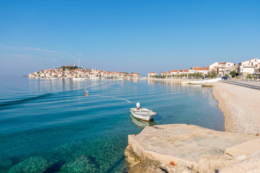a small boat in the water next to a beach at Apartments Katja in Primošten