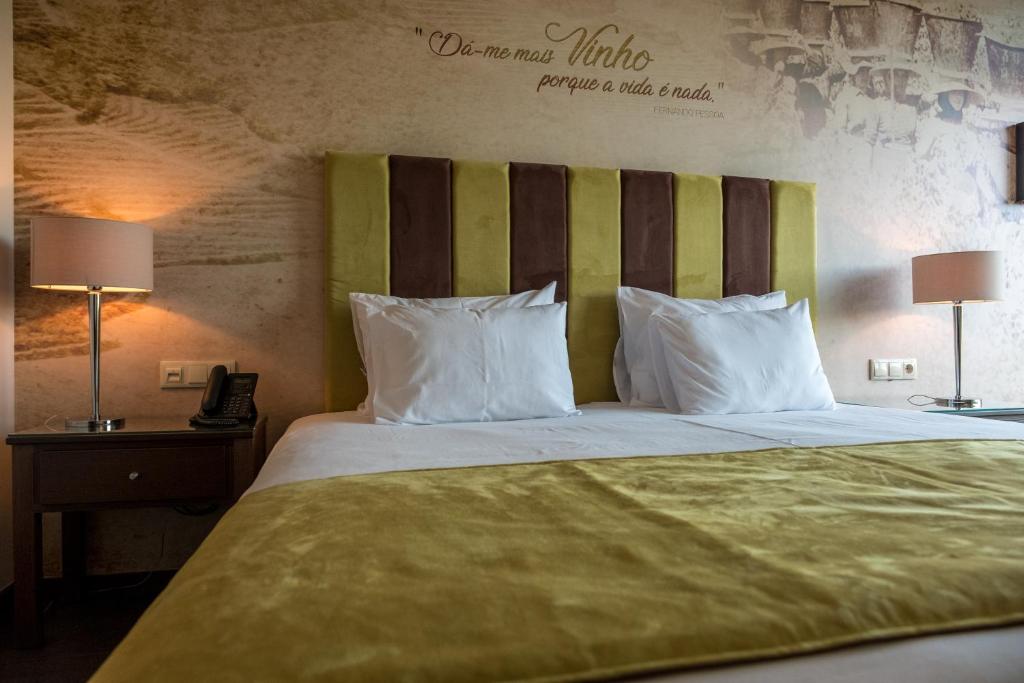a bed with white pillows and a green headboard at Vila Gale Douro Vineyards in Armamar