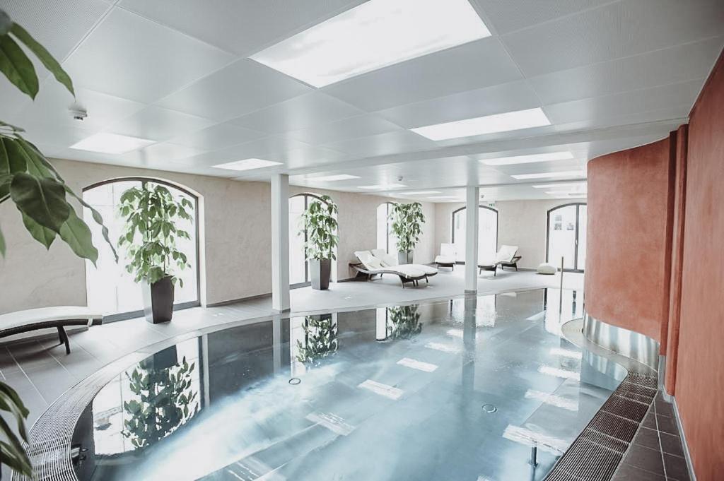 a large swimming pool with plants in a building at Hotel Freihof in Prichsenstadt