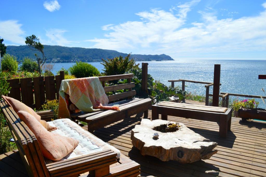 eine Terrasse mit Bänken, einem Tisch und dem Meer in der Unterkunft Cabañas Fischer SpA in Niebla