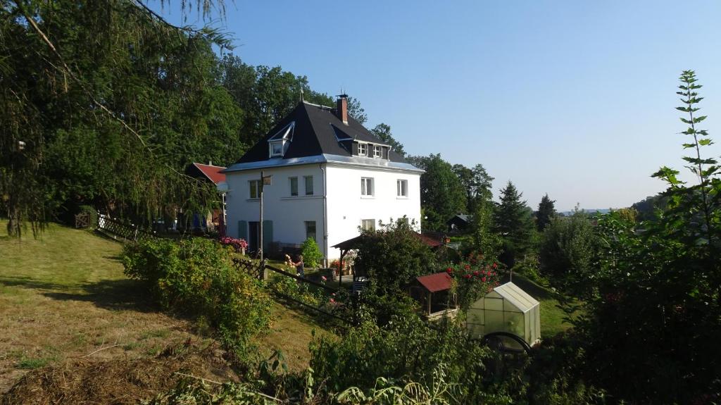ein weißes Haus mit schwarzem Dach auf einem Hügel in der Unterkunft Ferienwohnung Erzgebirgswohnung Götze in Glashütte