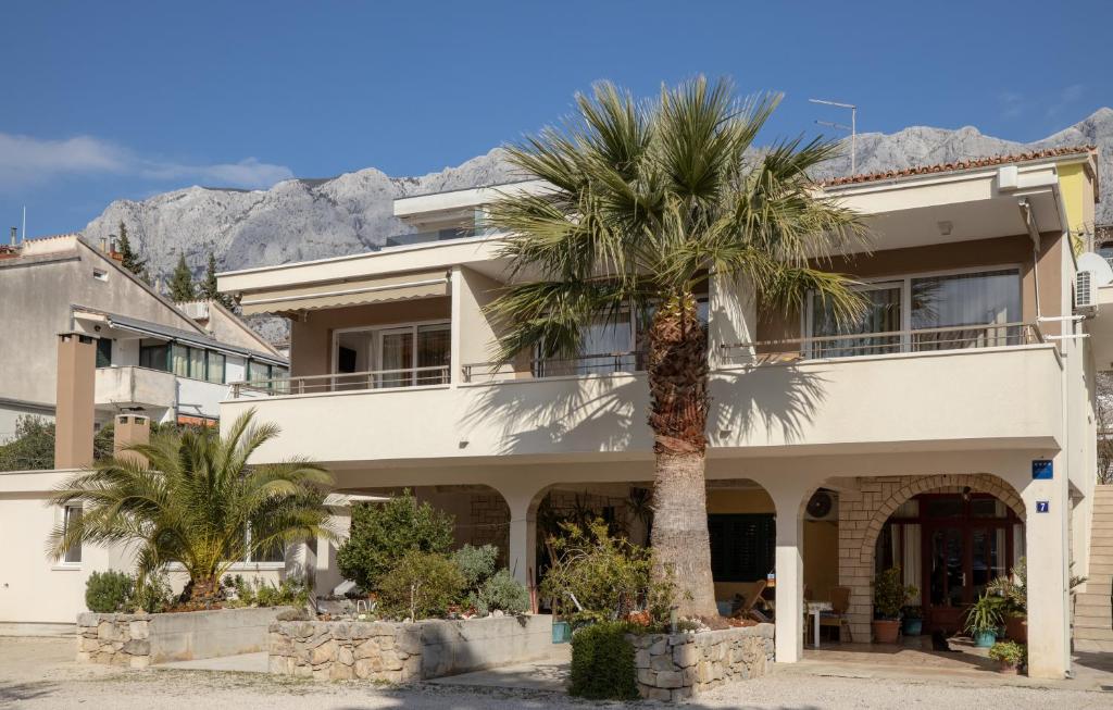 a building with a palm tree in front of it at Apartments Bogica in Makarska