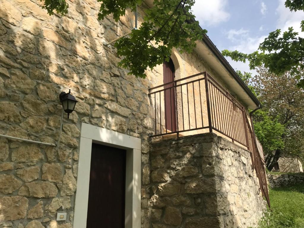 un edificio de piedra con balcón y puerta en Val Giardino 2 Casa Vacanze en Roccamorice