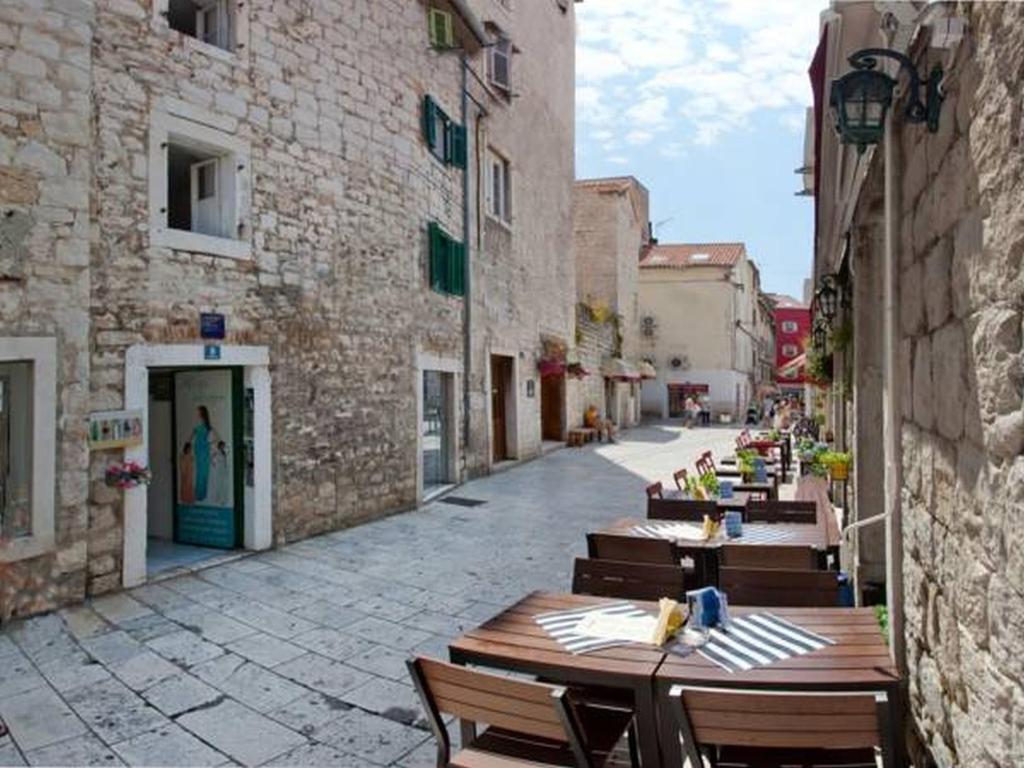 an empty street with wooden tables and chairs on a building at Kaleta in Split